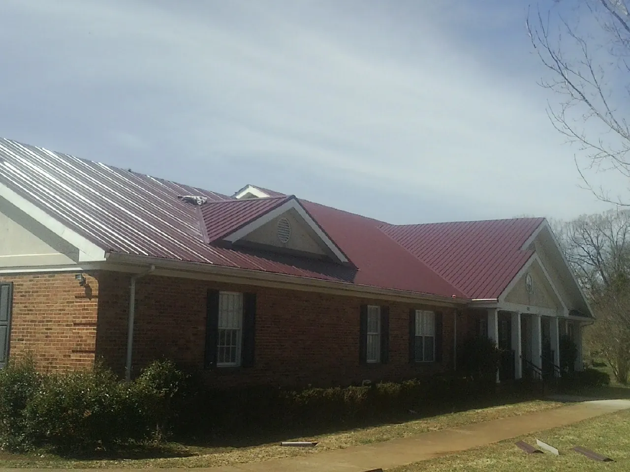 Red metal roof with gabled entries on a long brick building in New Roads