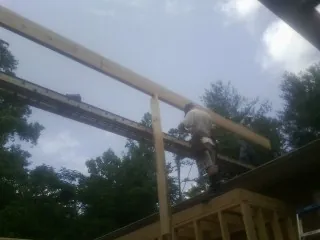 Carpenter setting a ridge beam over a new addition frame — Ice Dam Removal by Roofing Brothers in New Roads