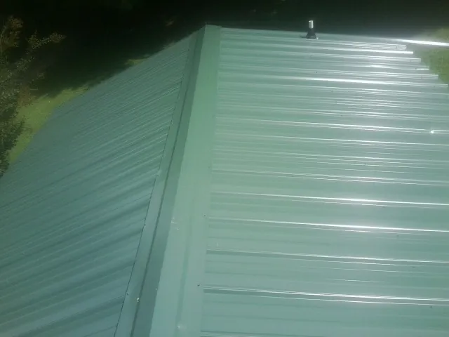 New green metal panels meeting at the ridge of a roof — Flat Roof Repair work by our crew in New Roads