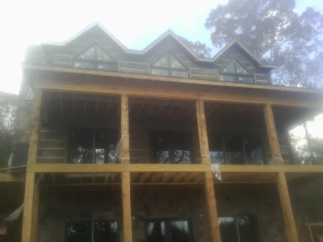 Dormers and porch framing on a large log home under construction — Roof Coating work by our crew in New Roads