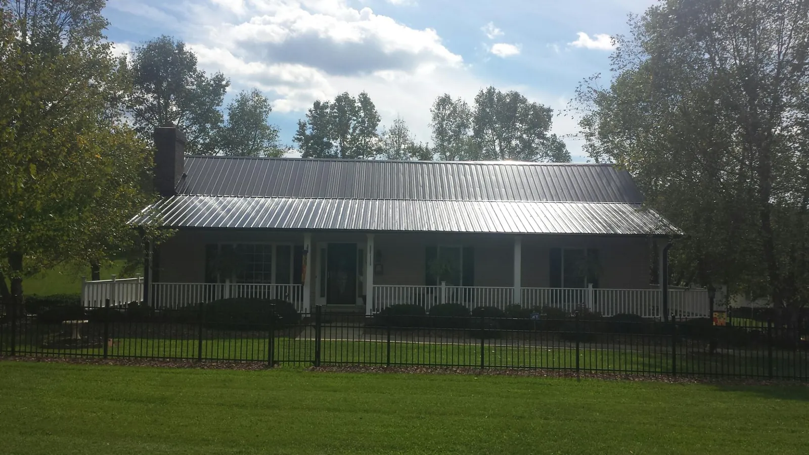 Gray metal roof on a brick ranch with a full width front porch — Gutter Guard Installation work by our crew in New Roads