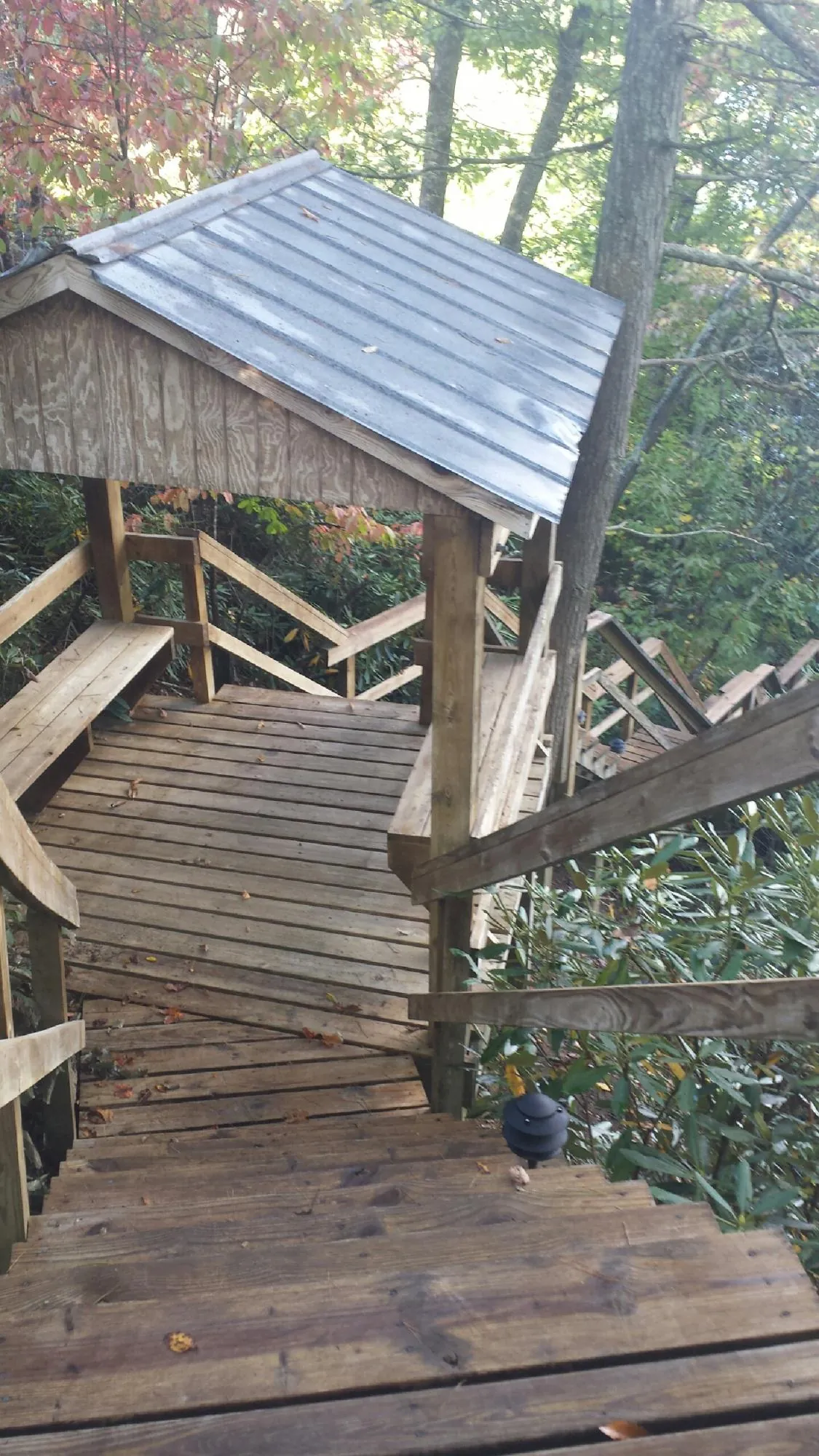 Metal roofed shelter over wooden steps on a wooded walkway — Skylight Repair & Installation work by our crew in New Roads