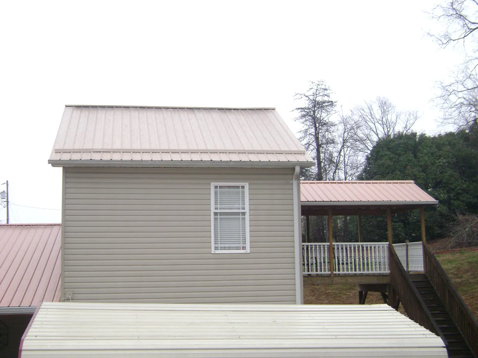 Tan metal roofs on a two story addition and attached porch, from a Roof Replacement job in New Roads
