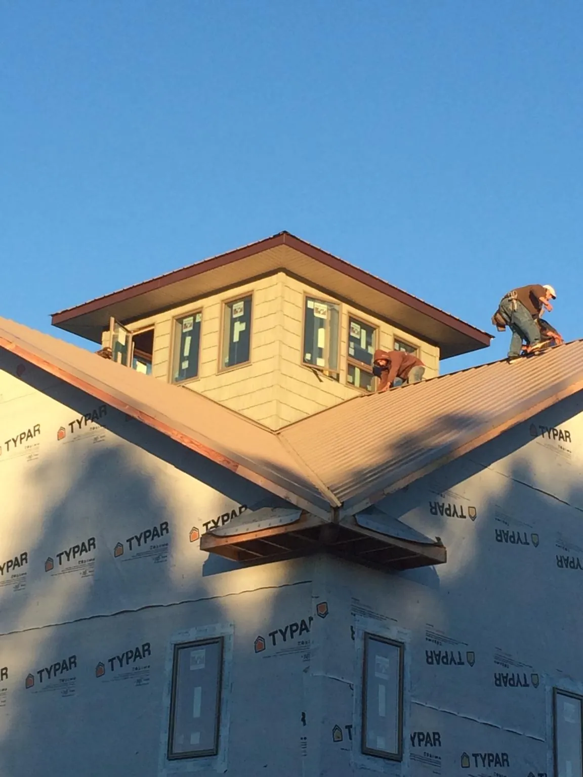 Roofers working around a rooftop cupola on a new metal roof at sunset — Roof Waterproofing in New Roads by Roofing Brothers